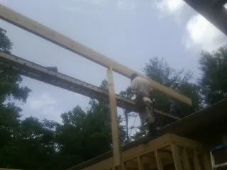 Carpenter setting a ridge beam over a new addition frame — Ice Dam Removal by Roofing Brothers in Mc Causland