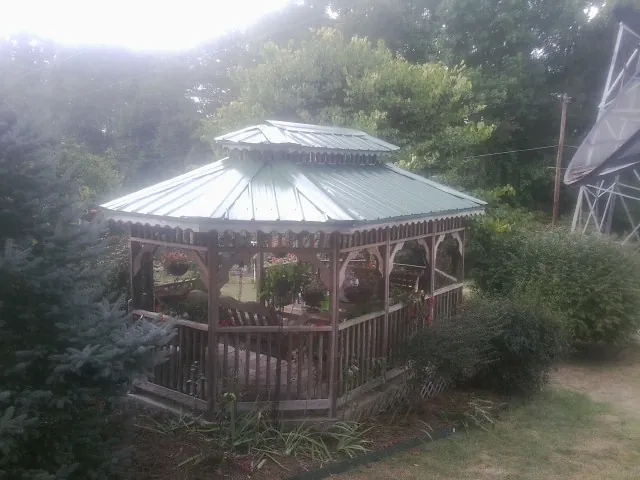 Green metal roof on a backyard gazebo surrounded by garden beds in Mc Causland