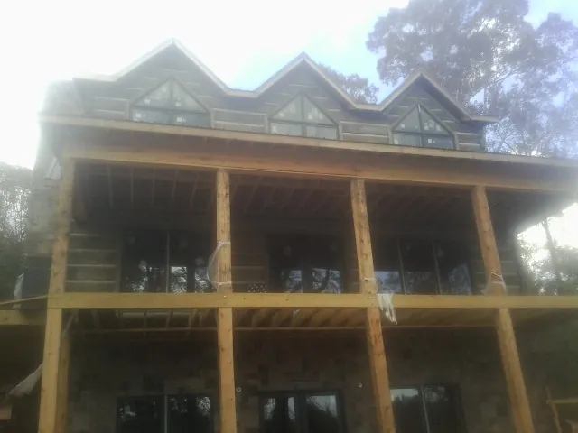 Dormers and porch framing on a large log home under construction — Roof Coating work by our crew in Mc Causland