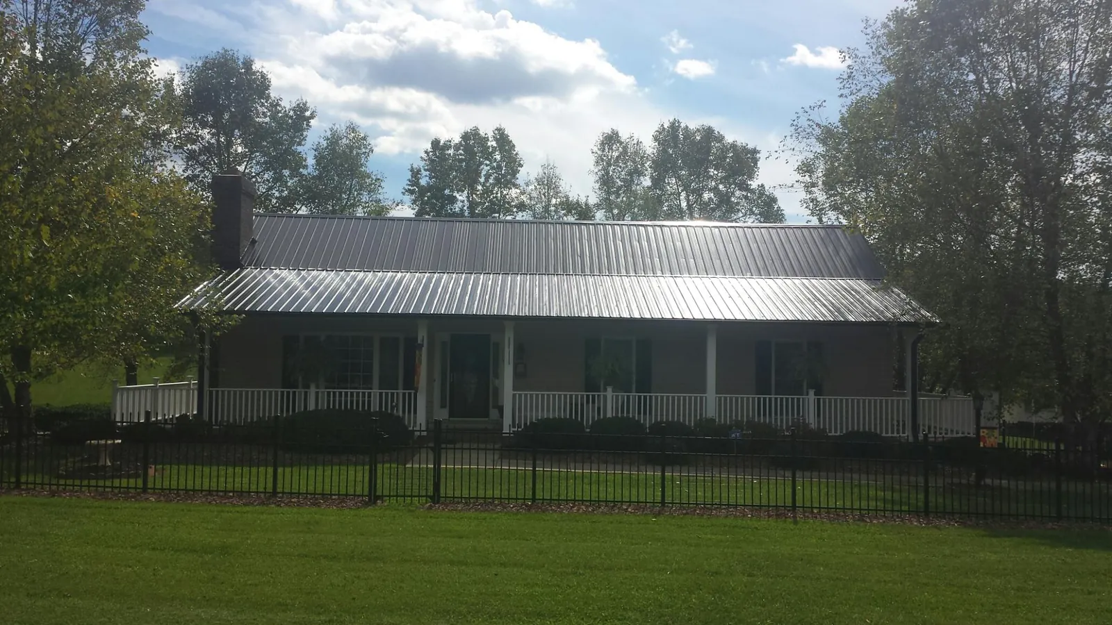 Gray metal roof on a brick ranch with a full width front porch — Gutter Guard Installation work by our crew in Mc Causland
