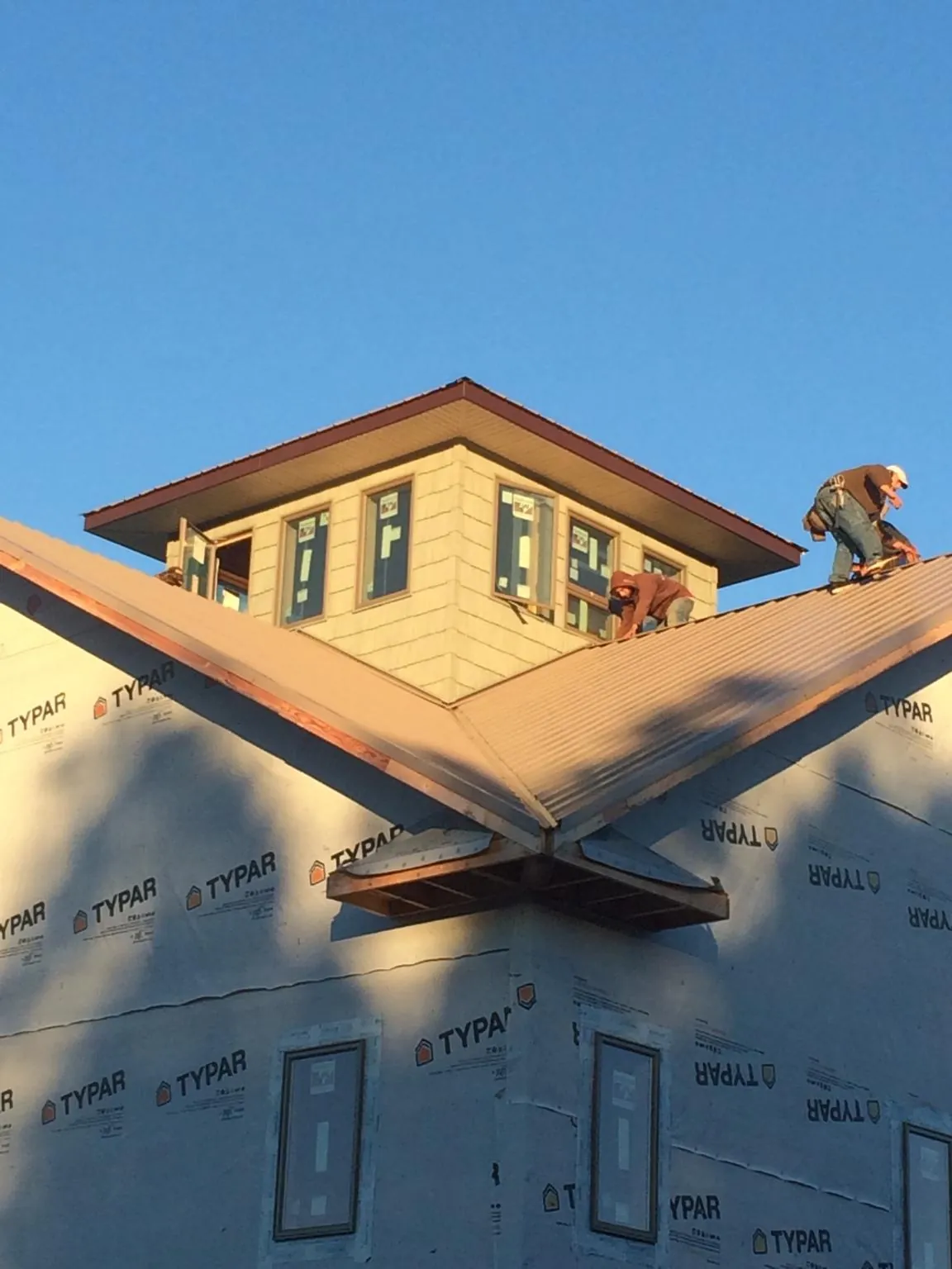 Roofers working around a rooftop cupola on a new metal roof at sunset — Roof Waterproofing in Mc Causland by Roofing Brothers